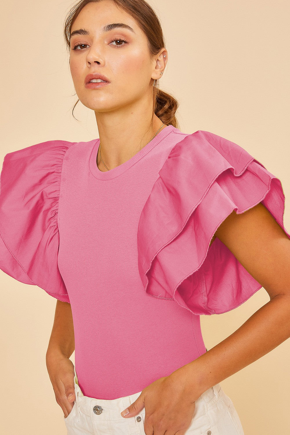 woman wearing a pink top with oversized ruffled sleeves and a fitted bodice