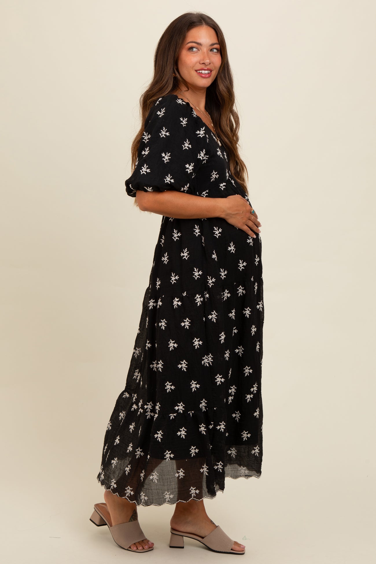woman wearing a black floral maternity maxi dress and holding her baby bump