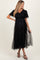 woman wearing a black maternity dress with tulle overlay and short sleeves, showcasing her baby bump