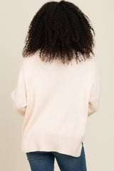 woman wearing a light pink oversized sweater from the back with a relaxed fit and ribbed hem