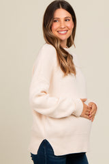woman wearing a light pink maternity sweater and holding her baby bump