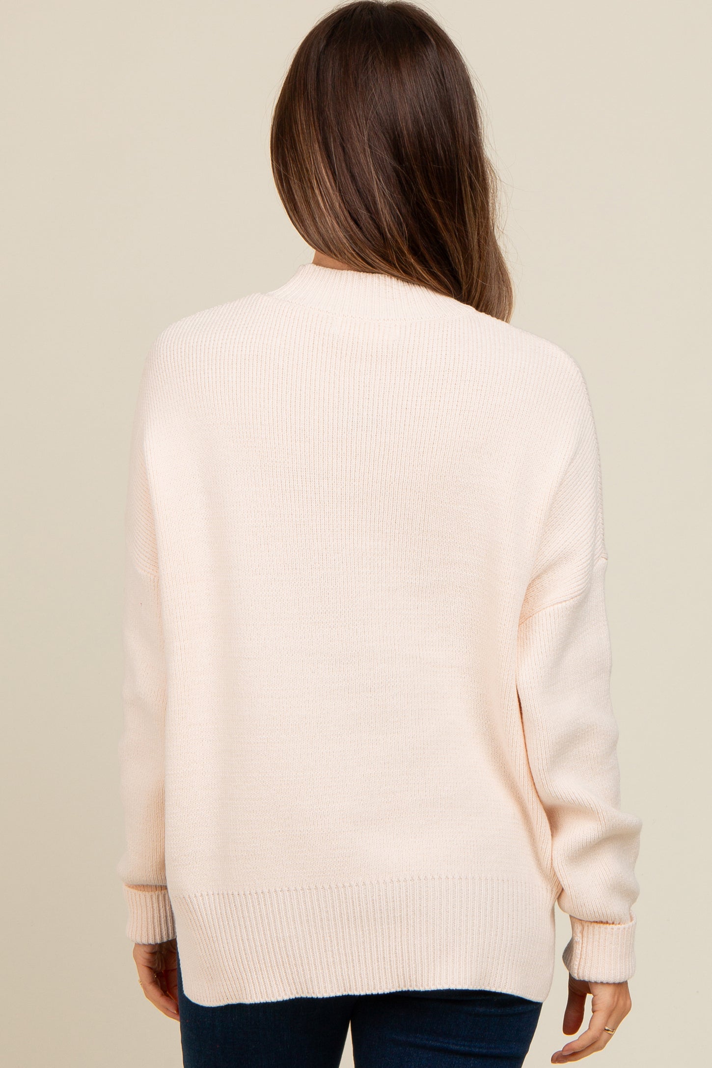 woman wearing a soft pink oversized maternity sweater, viewed from the back