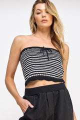 woman wearing a black and white striped strapless crop top with ruffle hem and front tie detail