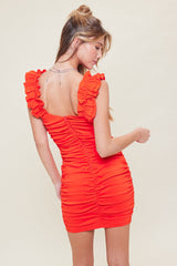 woman wearing a red ruched mini dress with ruffle sleeves, showcasing the back and side view