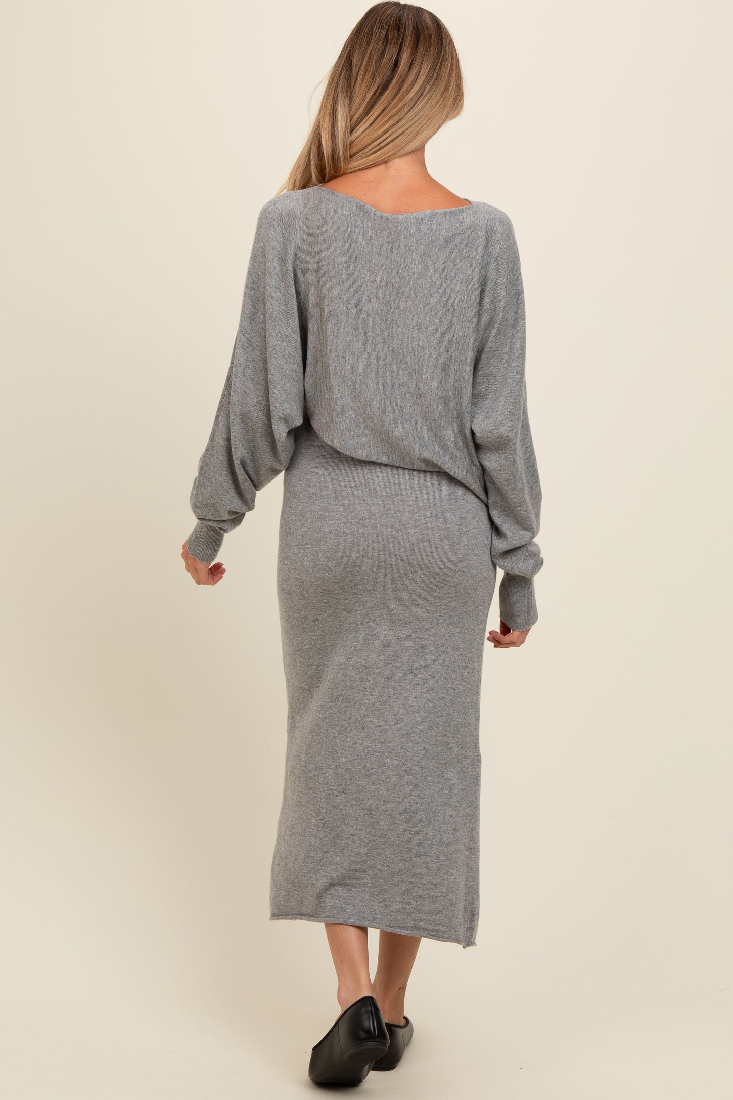 woman wearing a gray long sleeve maternity dress with a loose fit and mid-calf length, showing her back