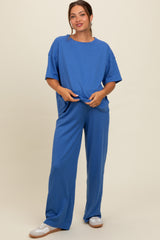 woman wearing a blue maternity loungewear set with a loose top and wide-leg pants, showcasing her baby bump