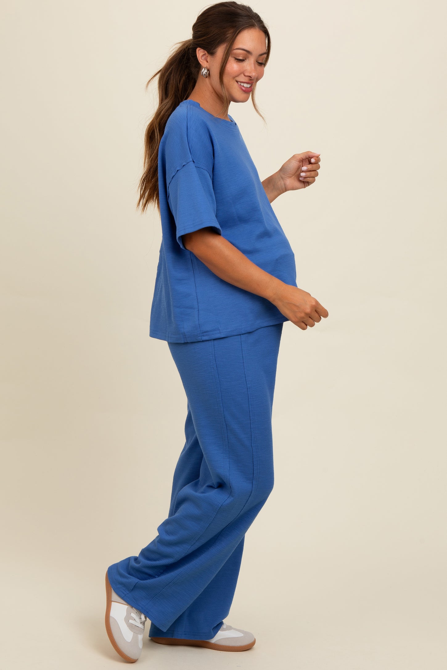 woman wearing a blue maternity loungewear set with short sleeves and wide-leg pants, showing her baby bump