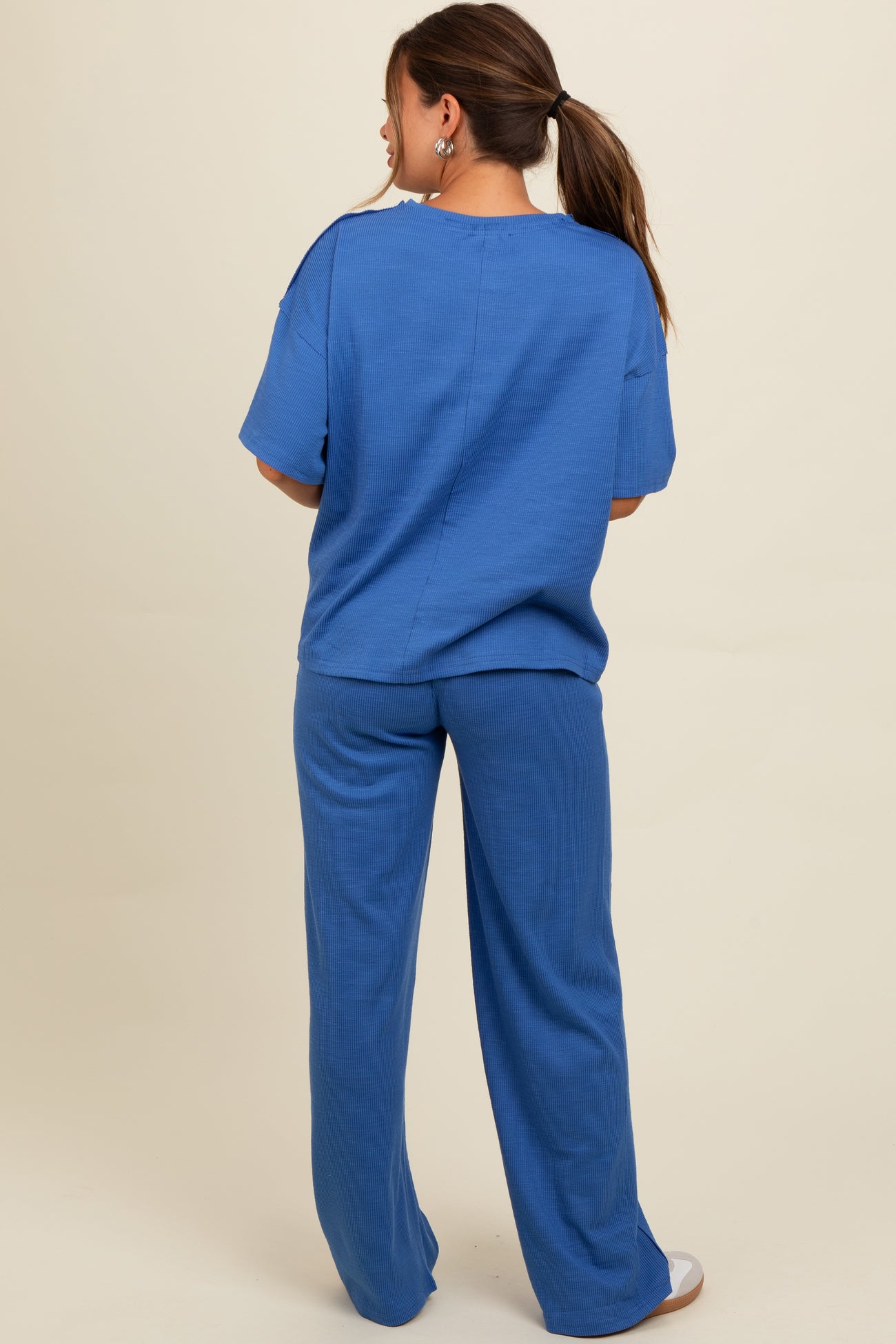 woman wearing a blue ribbed maternity lounge set, showing the back view with loose top and wide-leg pants