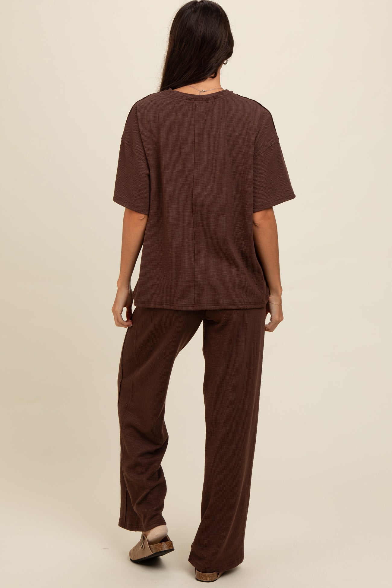 woman wearing a brown oversized short sleeve top and matching wide-leg pants, viewed from the back