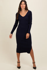 woman wearing a navy ribbed midi dress with long sleeves and a side slit, standing in a relaxed pose