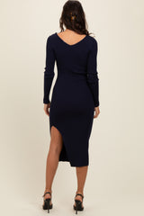 woman wearing a navy ribbed midi dress with long sleeves and a side slit, showing the back view