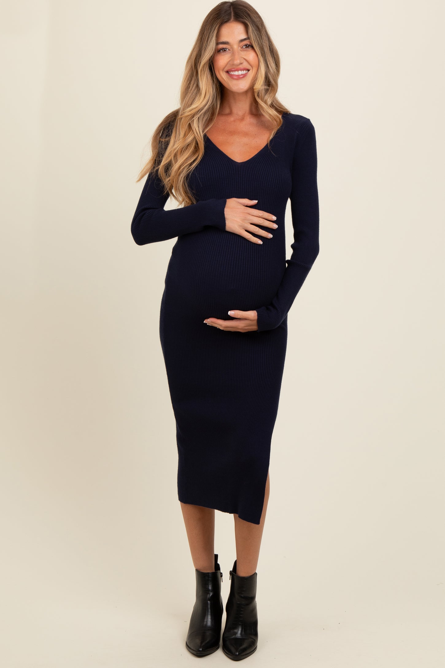 woman wearing a navy blue ribbed long sleeve maternity dress and holding her baby bump
