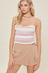woman wearing a pink and white striped strapless top with a ruffled hem and beige high-waisted shorts