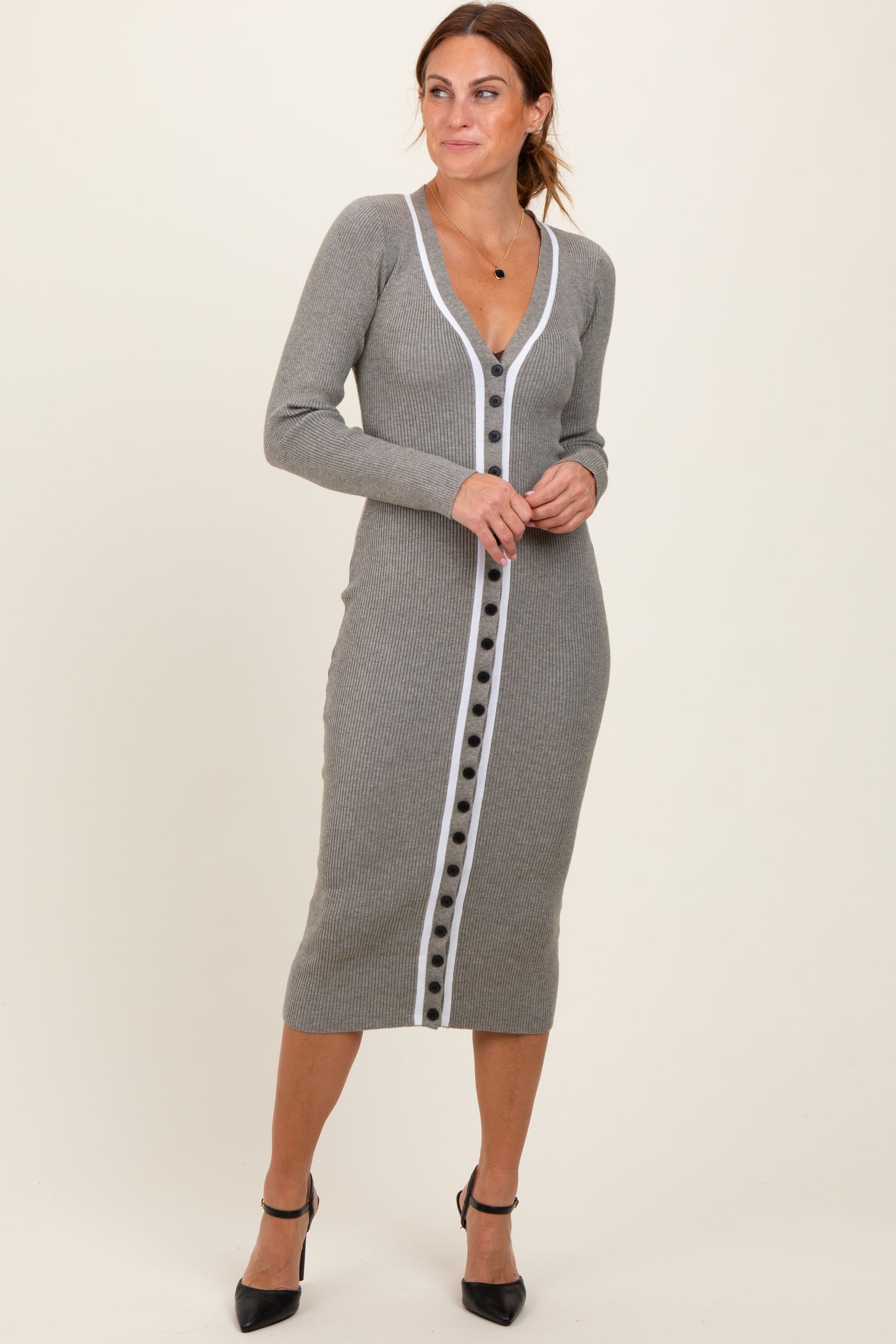 woman wearing a grey ribbed midi dress with a deep v-neck and contrasting white button detailing