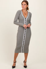 woman wearing a grey ribbed midi dress with a deep v-neck and contrasting white button detailing