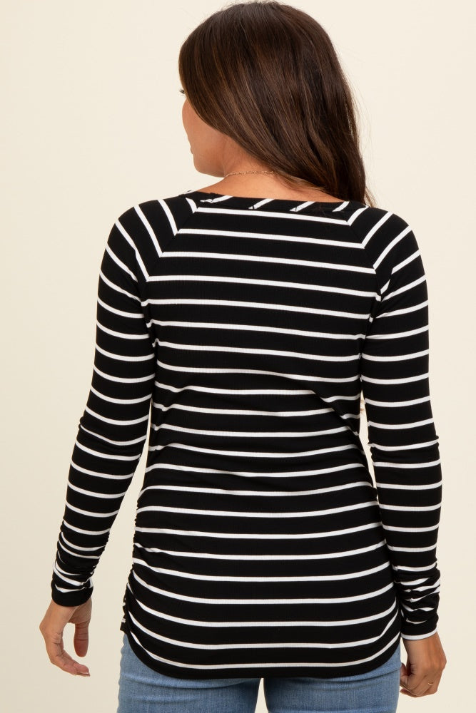 woman wearing a black and white striped maternity top with long sleeves and a ruched side detail