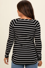 woman wearing a black and white striped maternity top with long sleeves and a ruched side detail