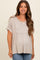woman wearing a taupe maternity top with a flared hem and short sleeves, showcasing her baby bump