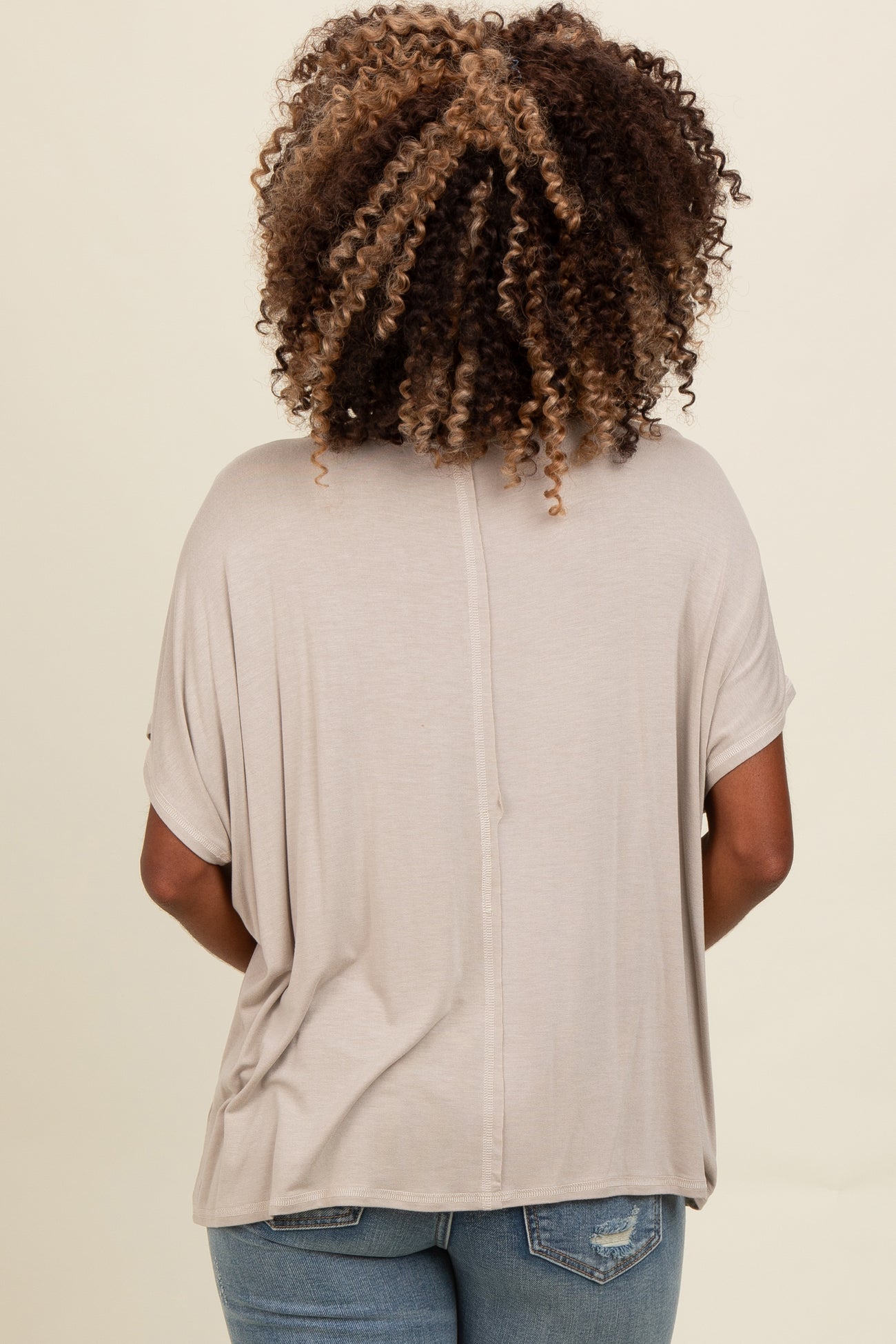 woman wearing a taupe short sleeve loose fit top with a round neckline, viewed from the back