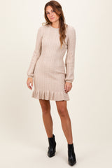 woman wearing a beige cable knit sweater dress with puff sleeves and a ruffled hem, paired with black ankle boots