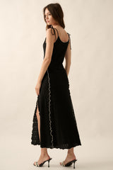 woman wearing a black lace maxi dress with tie straps and side slits, standing with her back to the camera