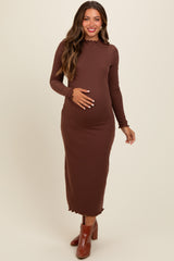woman wearing a brown ribbed maternity dress with a scalloped neckline and long sleeves, holding her baby bump
