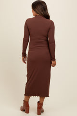 woman wearing a brown ribbed maternity dress with long sleeves and a midi length, showing a slightly flared hemline