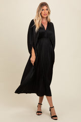 woman wearing a black pleated maxi dress with a deep v-neckline and batwing sleeves