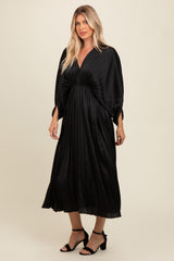 woman wearing a black pleated maxi dress with a deep v-neckline and oversized sleeves
