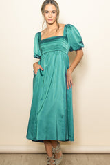 woman wearing a teal puff sleeve midi dress with a square neckline and gathered bodice