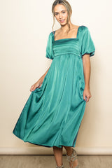 woman wearing a teal satin midi dress with puff sleeves and a square neckline