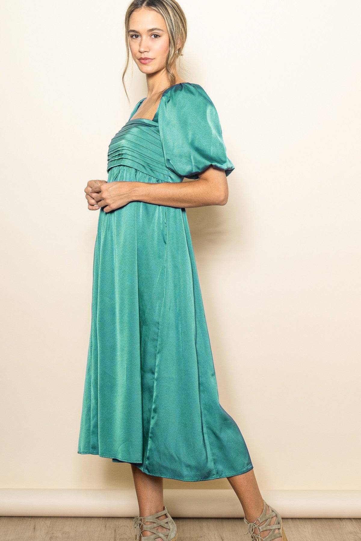 woman wearing a teal puff sleeve midi dress with a square neckline and pleated bodice