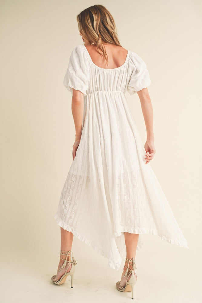 woman wearing a white puff sleeve midi dress with a back smocked detail and a high-low hemline