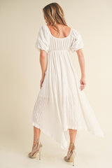 woman wearing a white puff sleeve midi dress with a back smocked detail and a high-low hemline