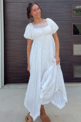woman wearing a white maxi dress with puff sleeves and intricate detailing, standing outdoors