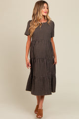woman wearing a brown and black checkered maternity dress with short sleeves and a tiered skirt, highlighting her baby bump