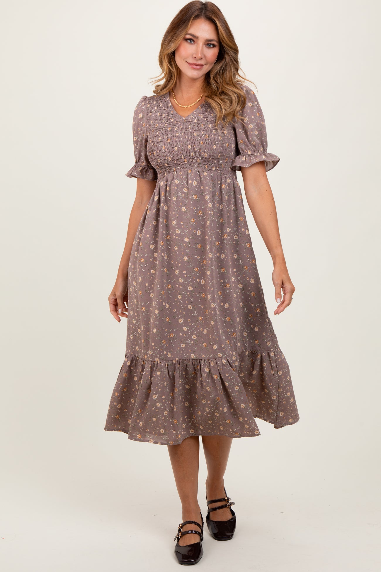 woman wearing a brown floral puff sleeve midi dress with a smocked bodice and a ruffled hem