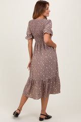 woman wearing a dusty mauve floral short sleeve dress with a smocked back and tiered hem, standing with her back to the camera