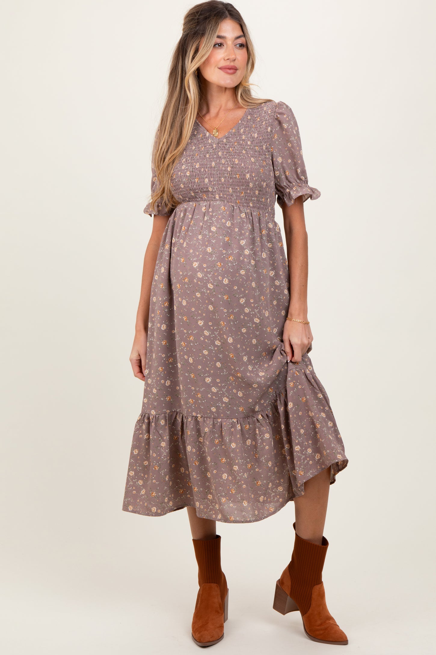 woman wearing a brown floral maternity dress with short puff sleeves and a tiered skirt, showing her baby bump