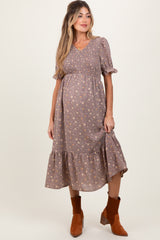 woman wearing a brown floral maternity dress with short puff sleeves and a tiered skirt, showing her baby bump