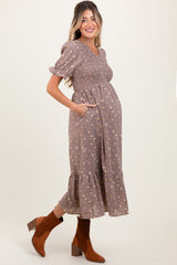 woman wearing a lavender floral maternity dress with puff sleeves and a tiered hem, showcasing her baby bump