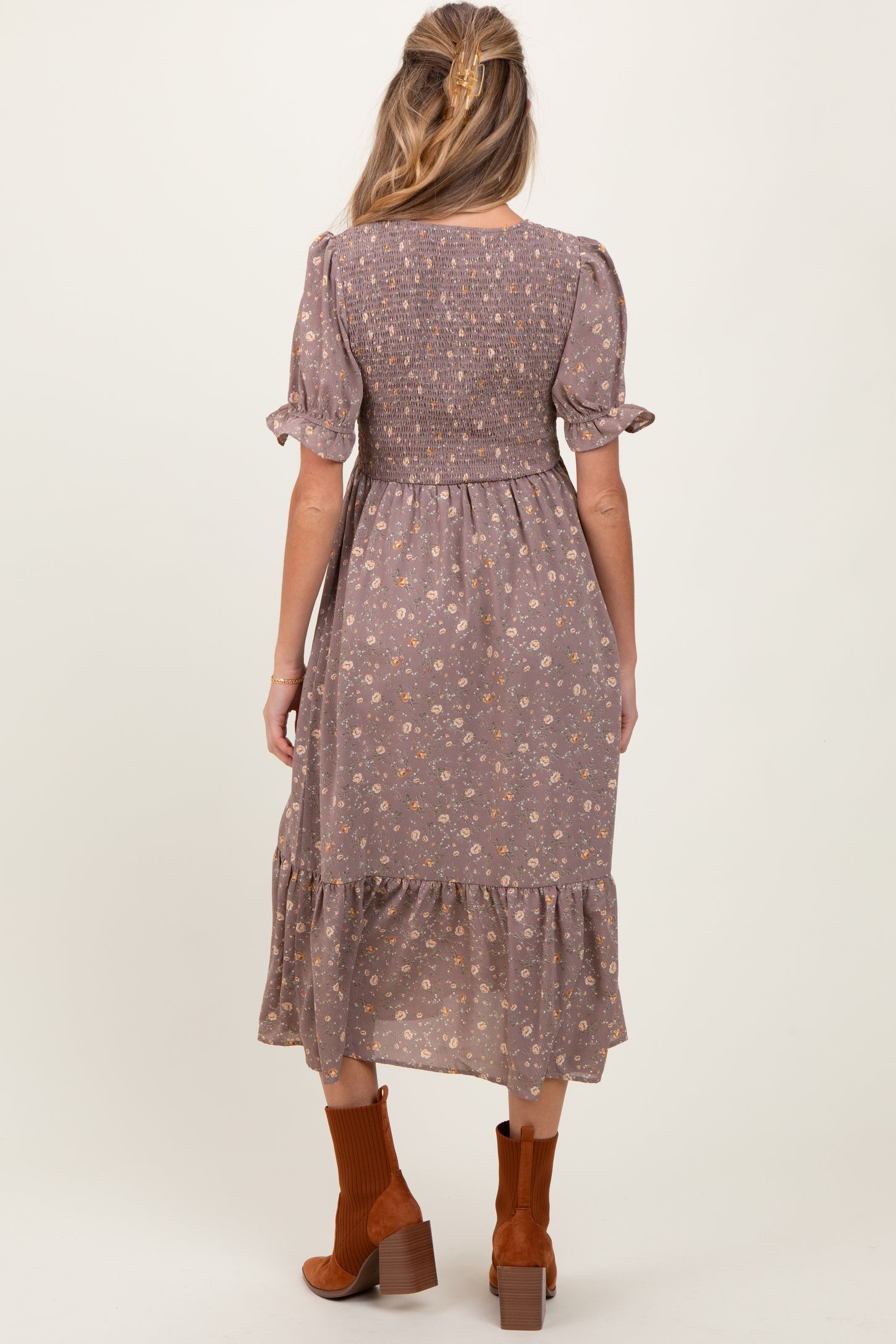 woman wearing a floral print maternity dress with short sleeves and a tiered hem, showing a baby bump