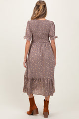 woman wearing a floral print maternity dress with short sleeves and a tiered hem, showing a baby bump