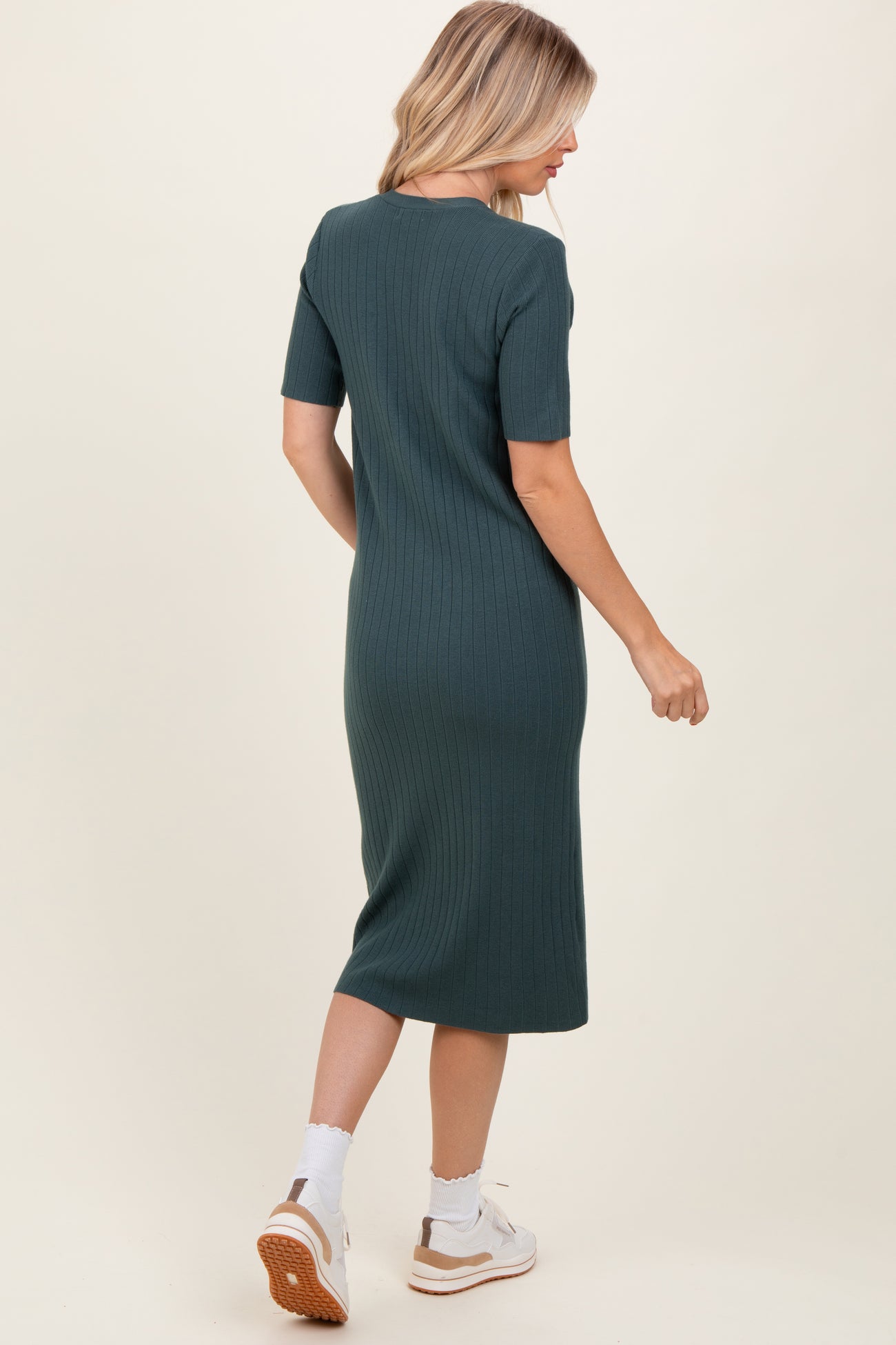 woman wearing a fitted green ribbed midi dress with short sleeves, seen from the back