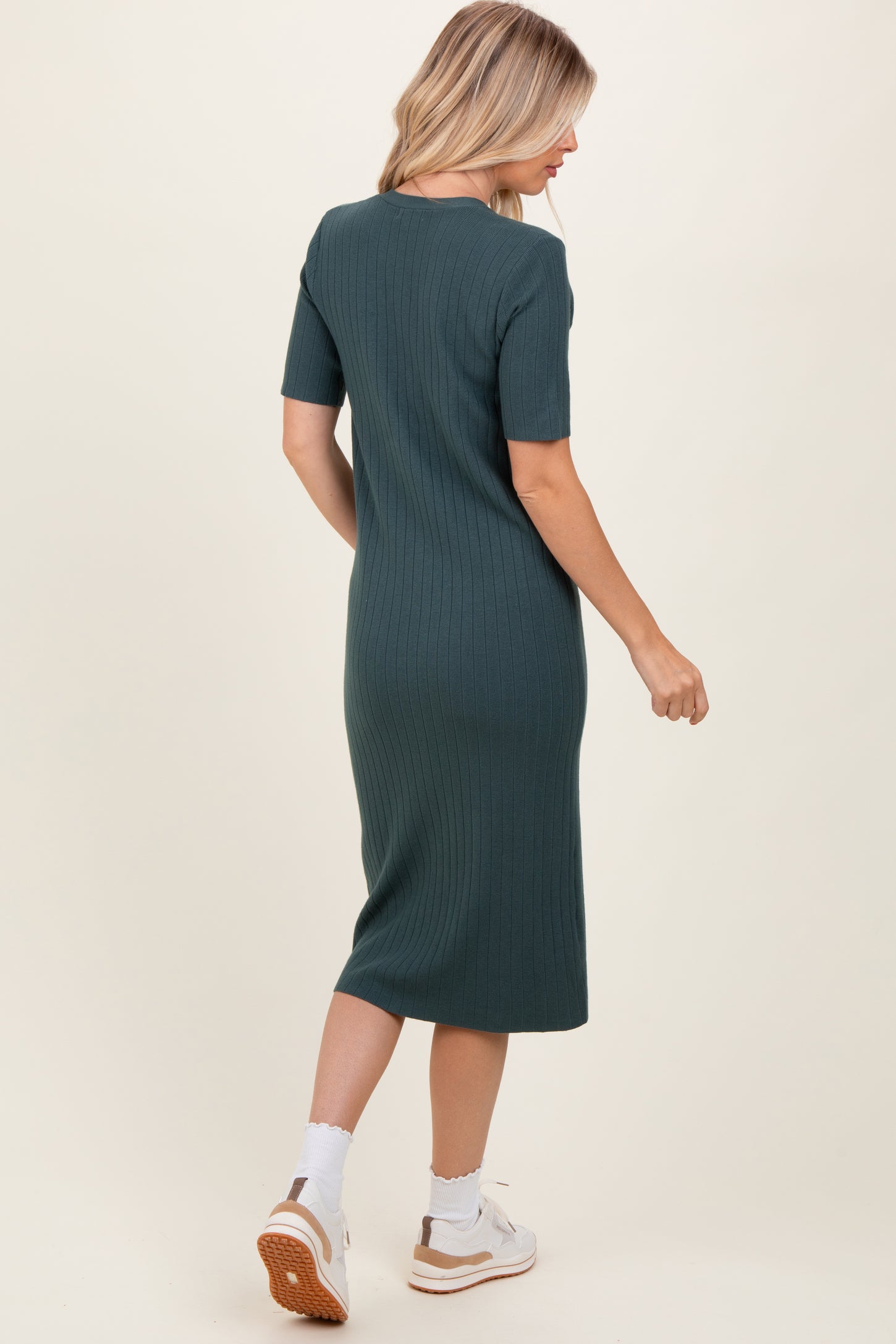 woman wearing a fitted green ribbed midi dress with short sleeves, seen from the back