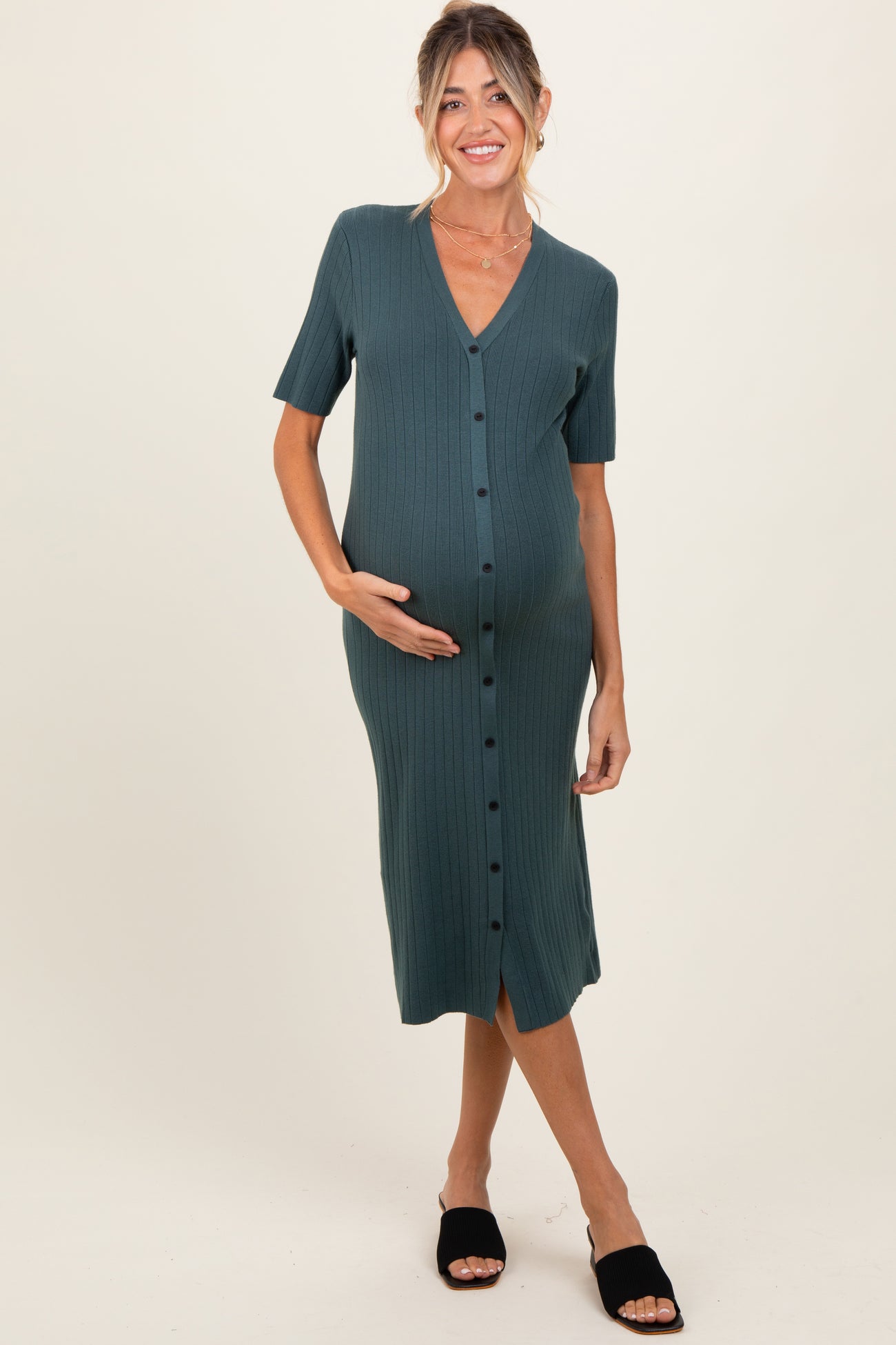 woman wearing a green ribbed maternity dress with buttons and short sleeves, showcasing her baby bump