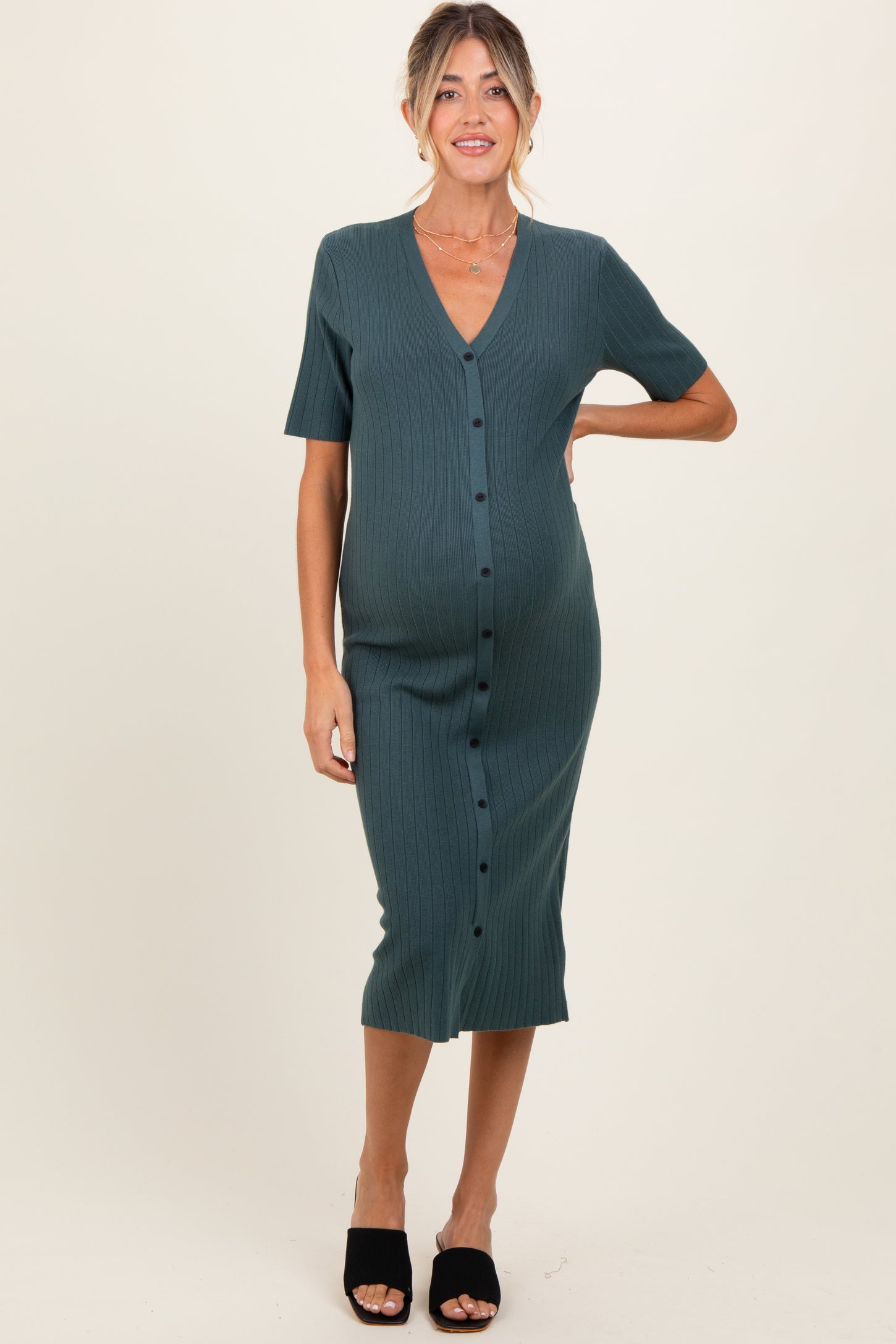 woman wearing a dark green ribbed maternity button-up dress with a v-neck and short sleeves, showing her baby bump