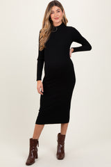 woman wearing a black ribbed maternity dress with long sleeves and a fitted silhouette, showing her baby bump