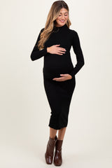 woman wearing a black ribbed maternity dress and holding her baby bump