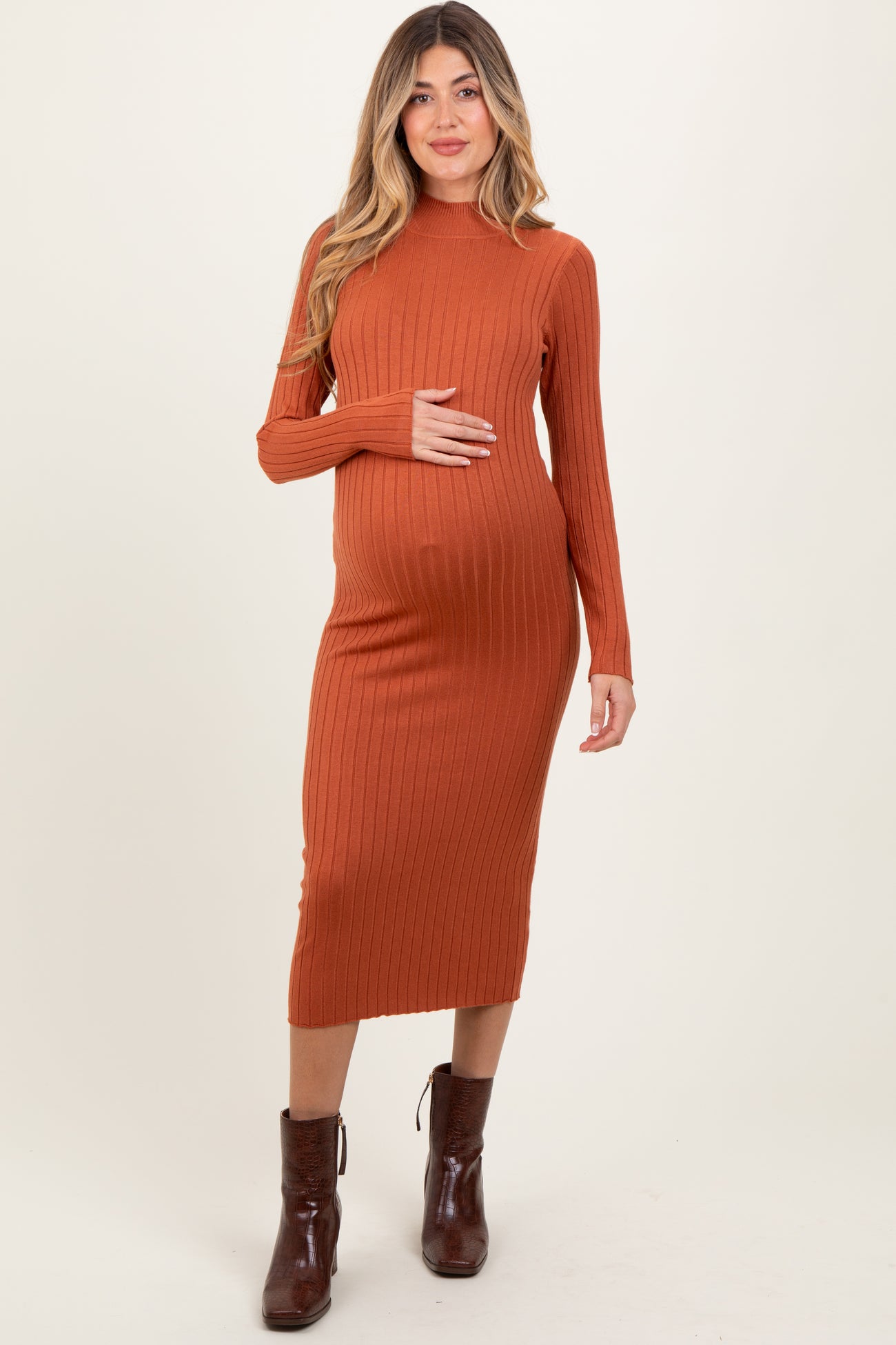 woman wearing an orange ribbed maternity dress with long sleeves and a visible baby bump